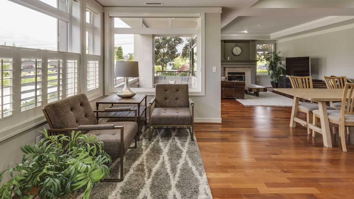 Sunlit living room with white plantation shutters across the windows and hardwood floors