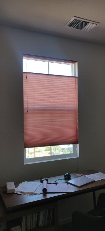 A coral cellular shade in an office