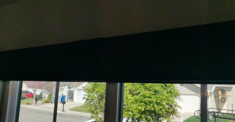 A solar shade holding the top of a window
